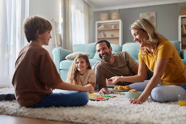 happy-parents-and-their-kids-playing-ludo-on-carpet-at-home-